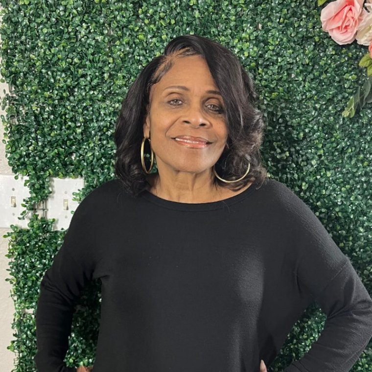 Patricia Woods smiling in front of a greenery-and-flower wall